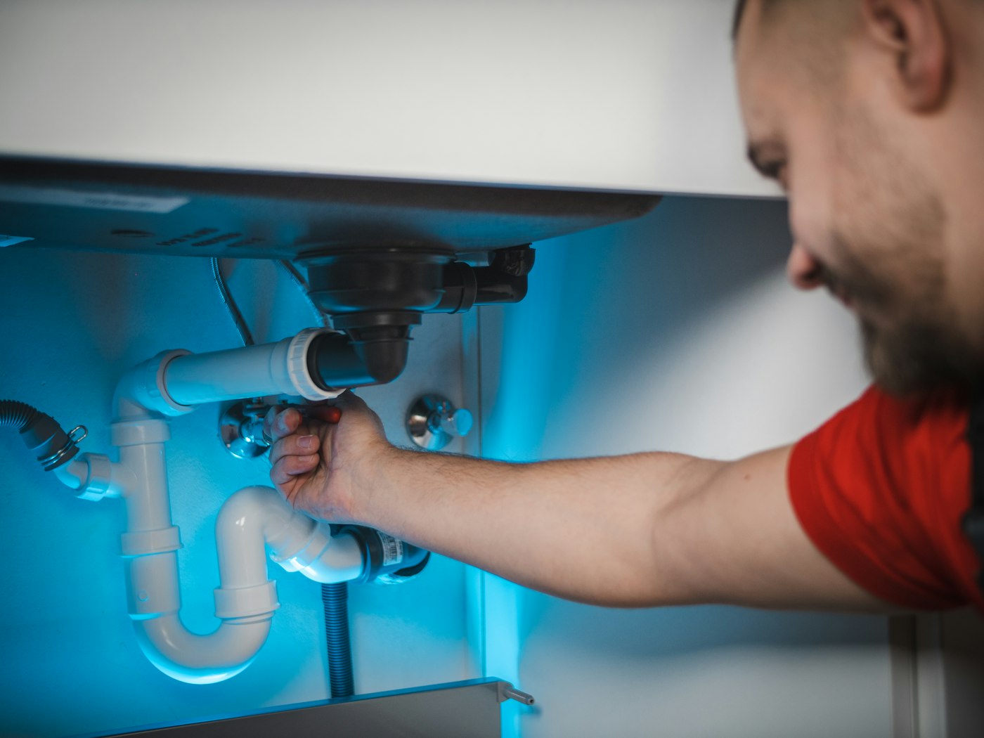 A plumber repairing pipes under a sink